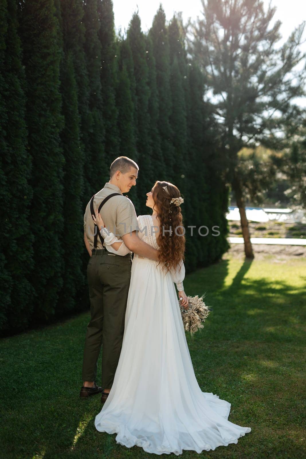 wedding walk of the bride and groom in a coniferous park in summer