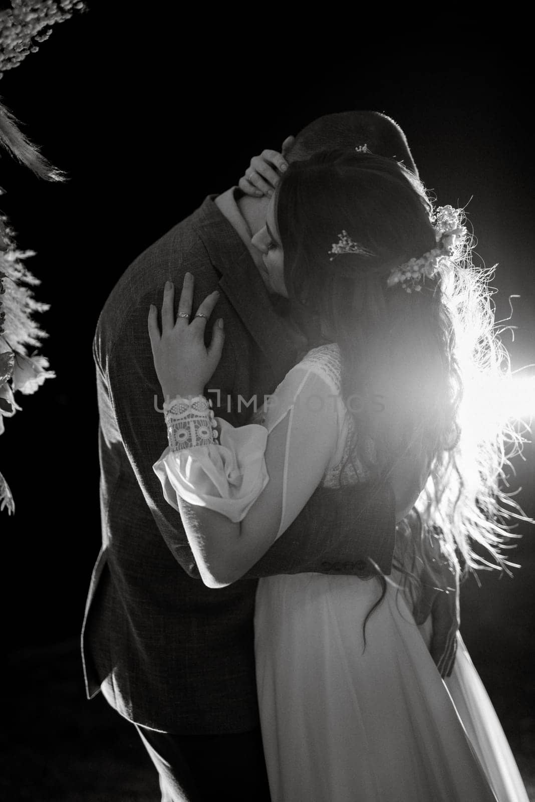 bride and groom against the backdrop of an evening wedding arch with warm live fire