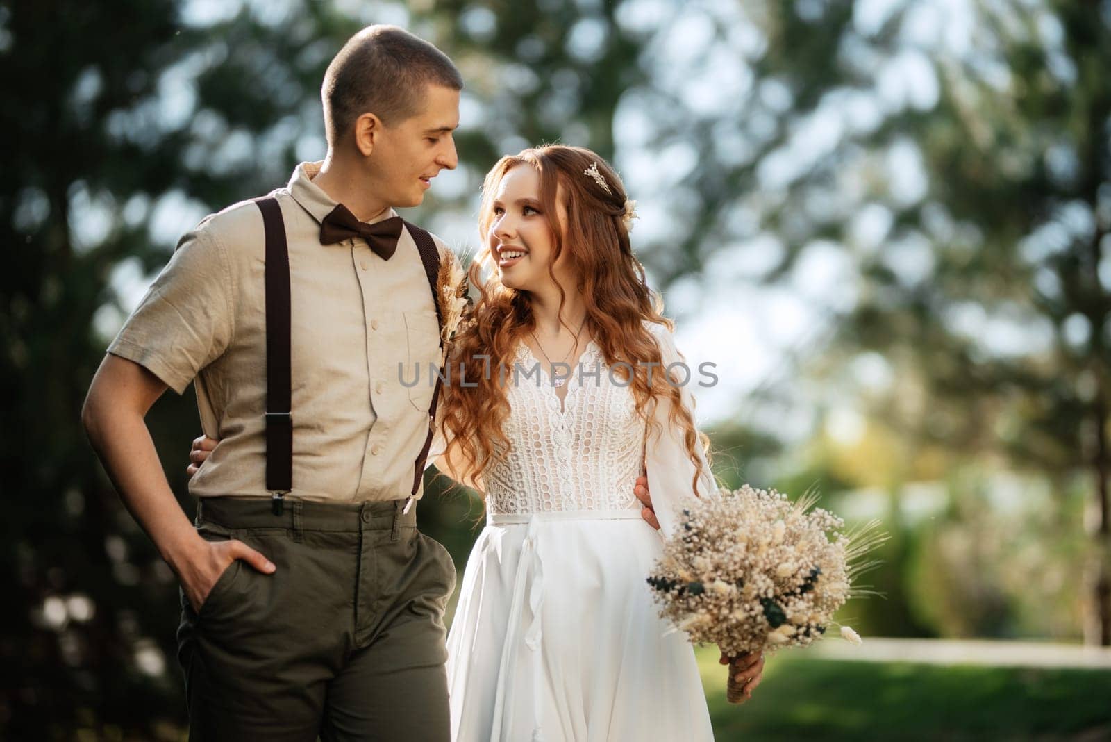 wedding walk of the bride and groom in a coniferous park in summer