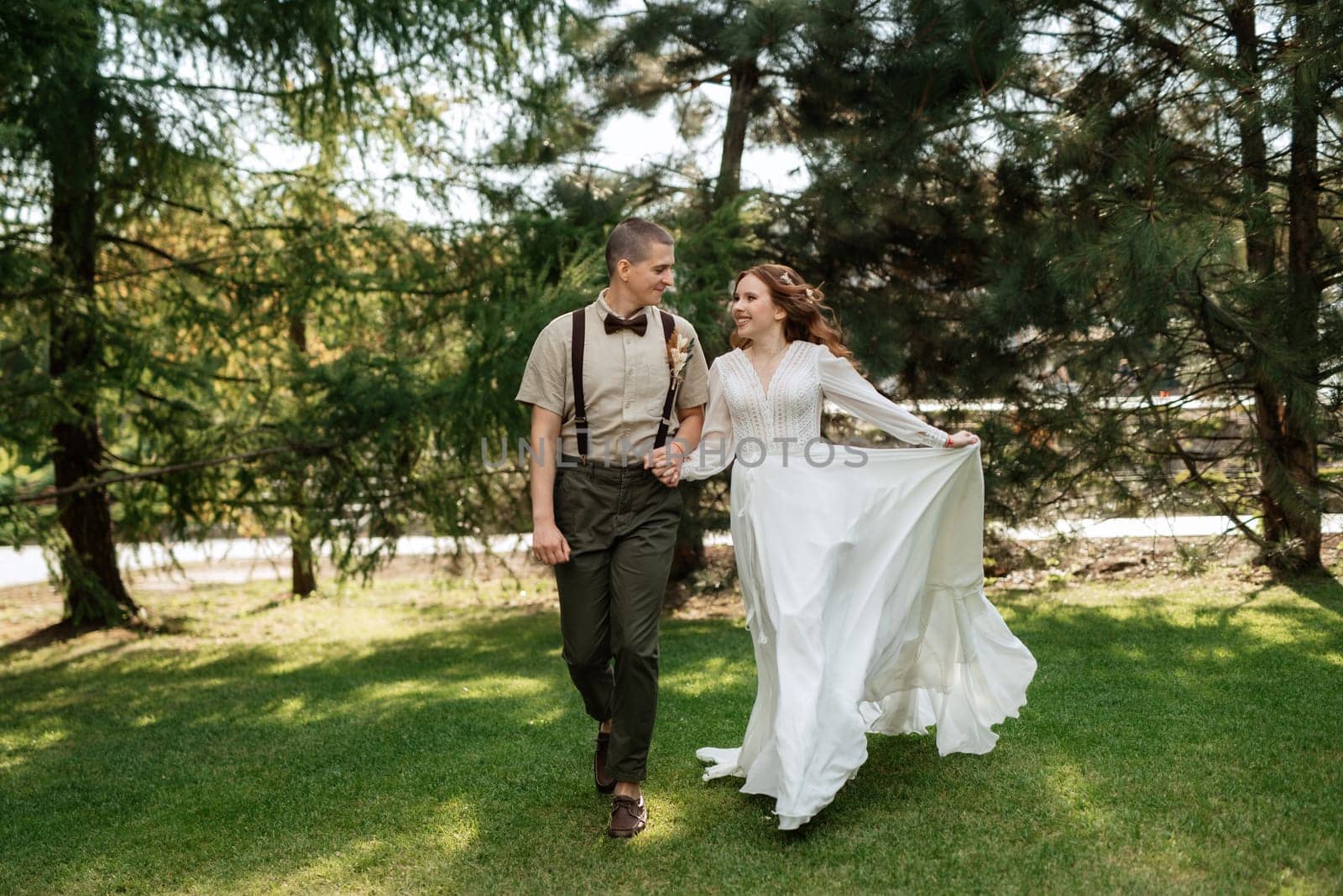 wedding walk of the bride and groom in a coniferous park in summer