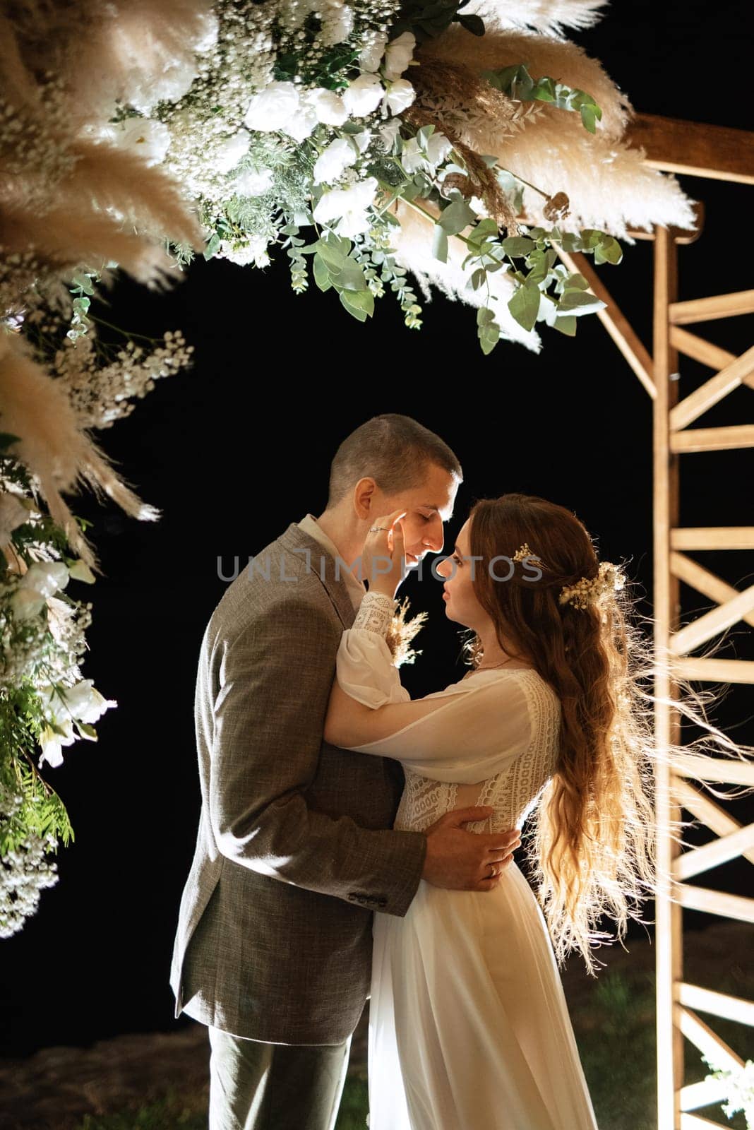 bride and groom against the backdrop of an evening wedding arch by Andreua