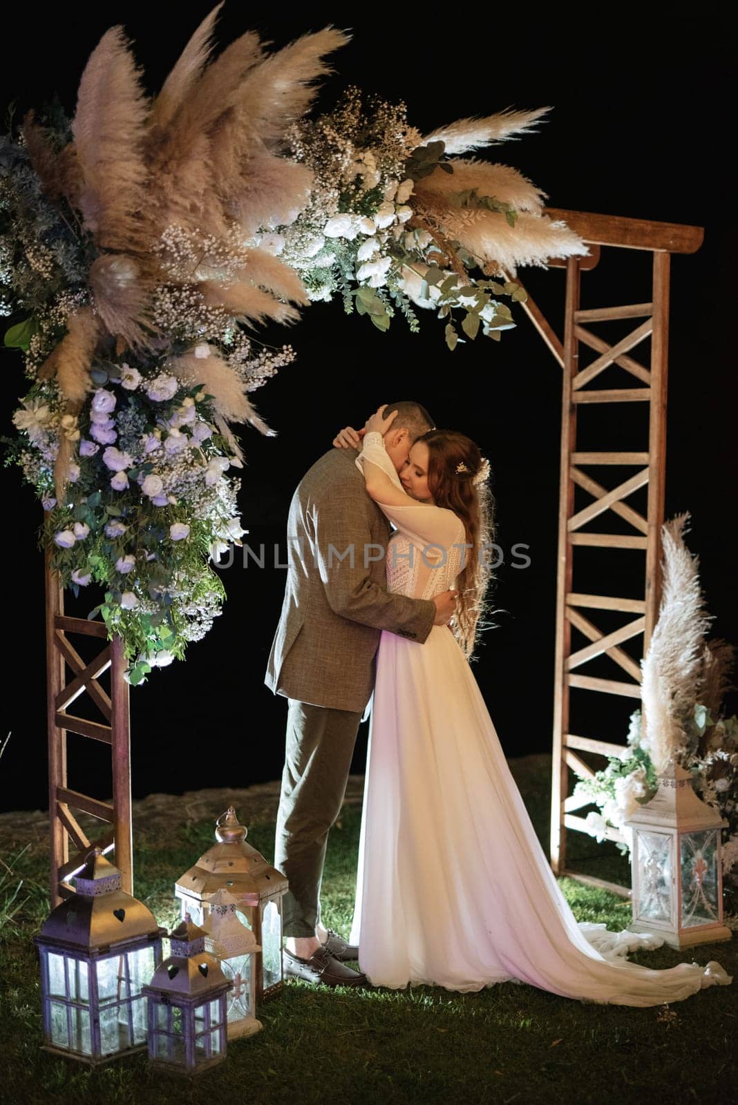 bride and groom against the backdrop of an evening wedding arch by Andreua