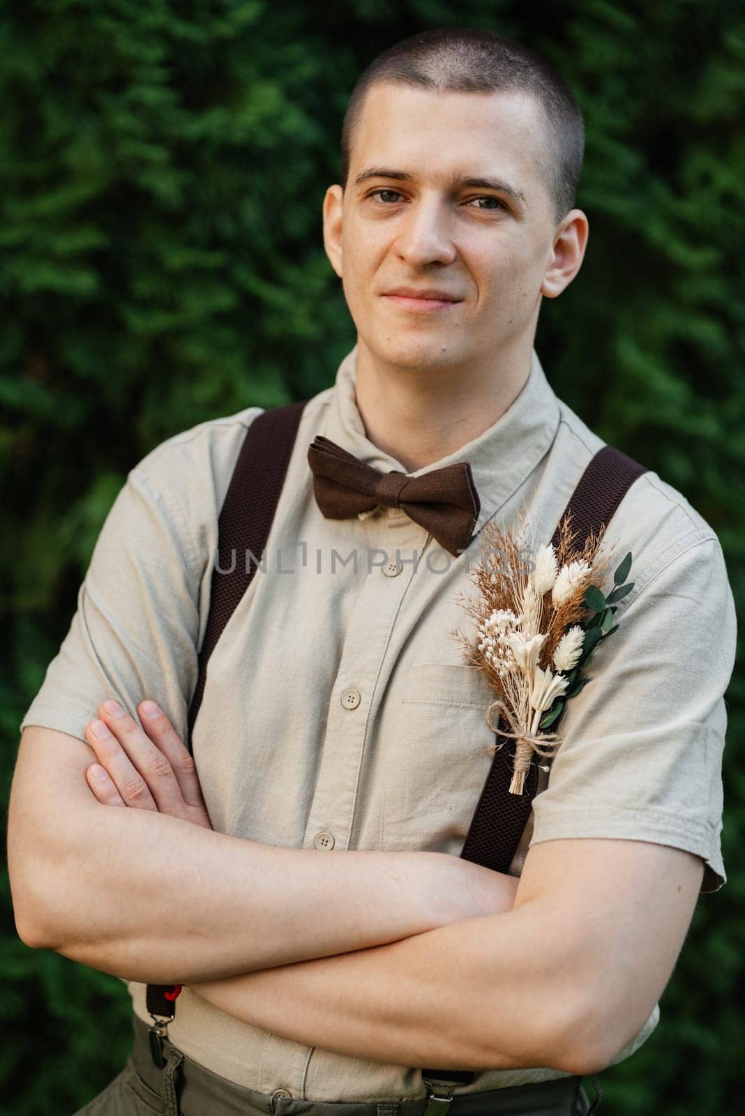 young guy the groom in the image in the style of boho on the background of green thuja