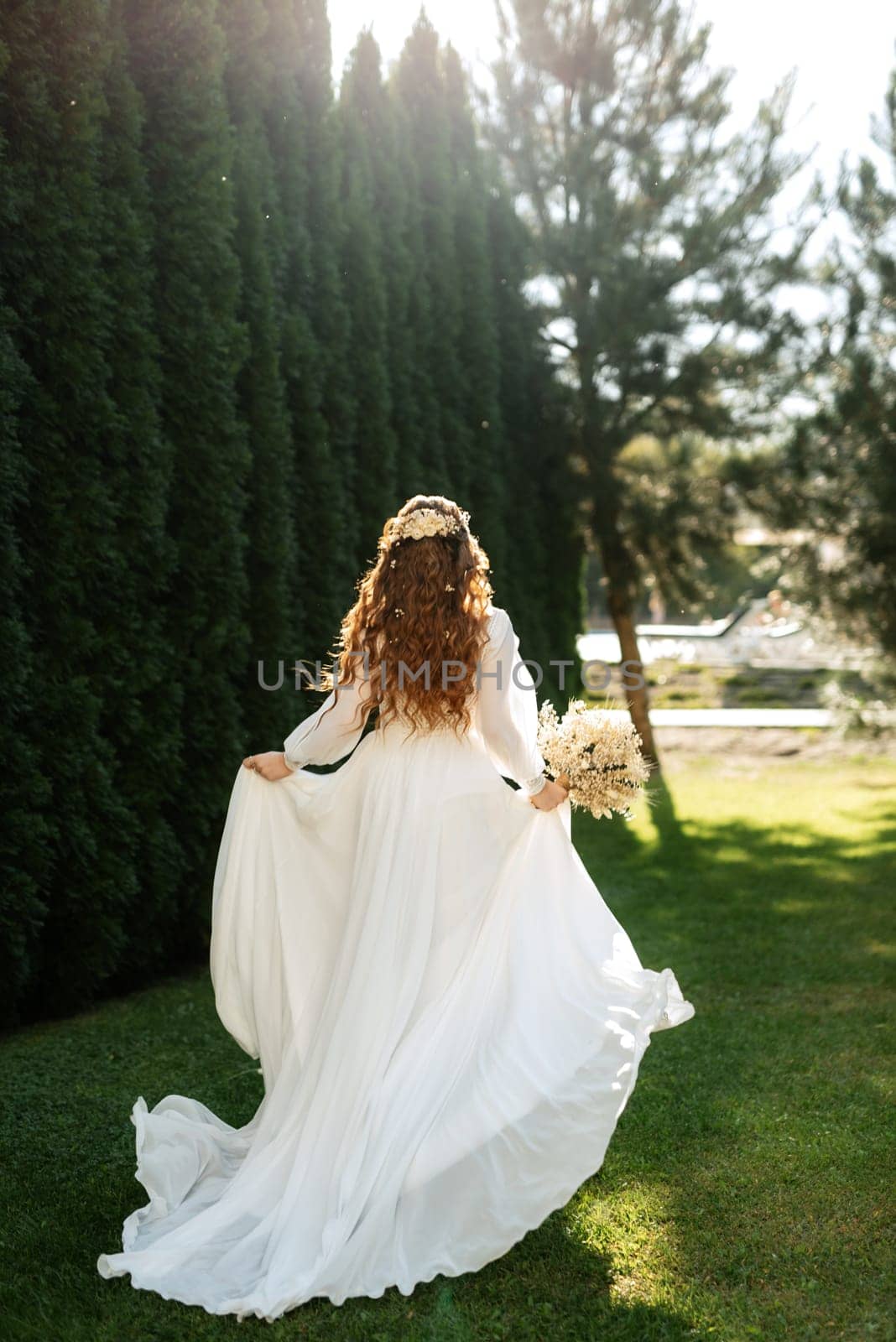 red-haired girl bride with a wedding bouquet on a meadow with green thuja