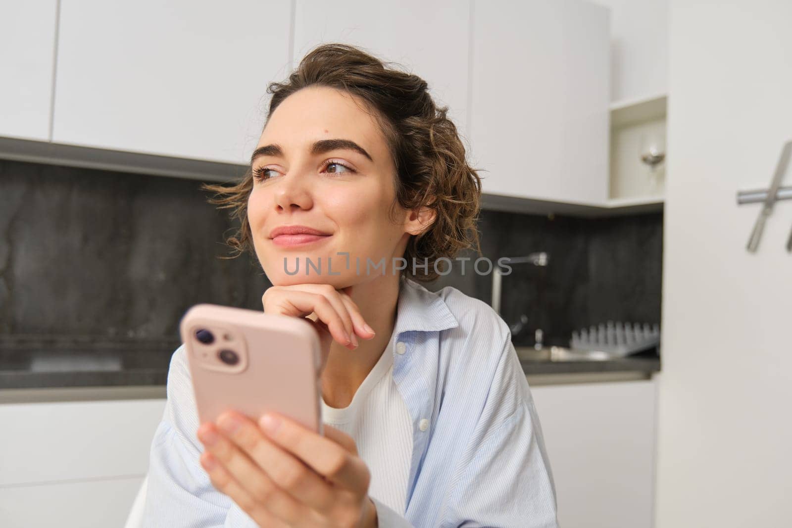 Portrait of beautiful woman at home, holding smartphone, online shopping from mobile phone app.