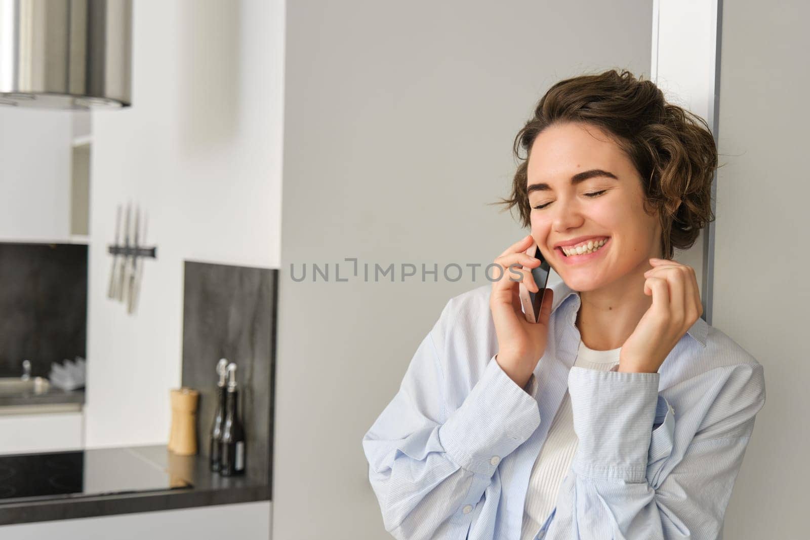 Image of happy woman talking on mobile phone, having a chat, using smartphone, laughing and smiling, calling from home.
