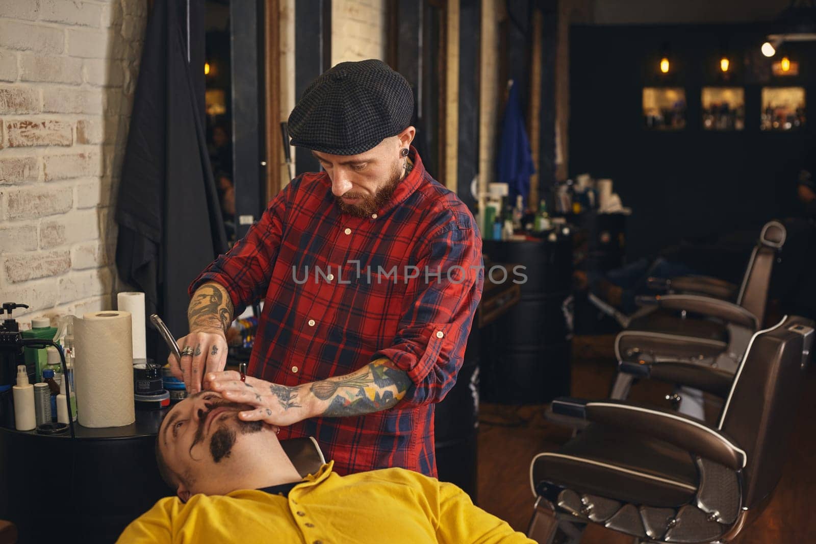 Client during beard shaving in barber shop by nazarovsergey