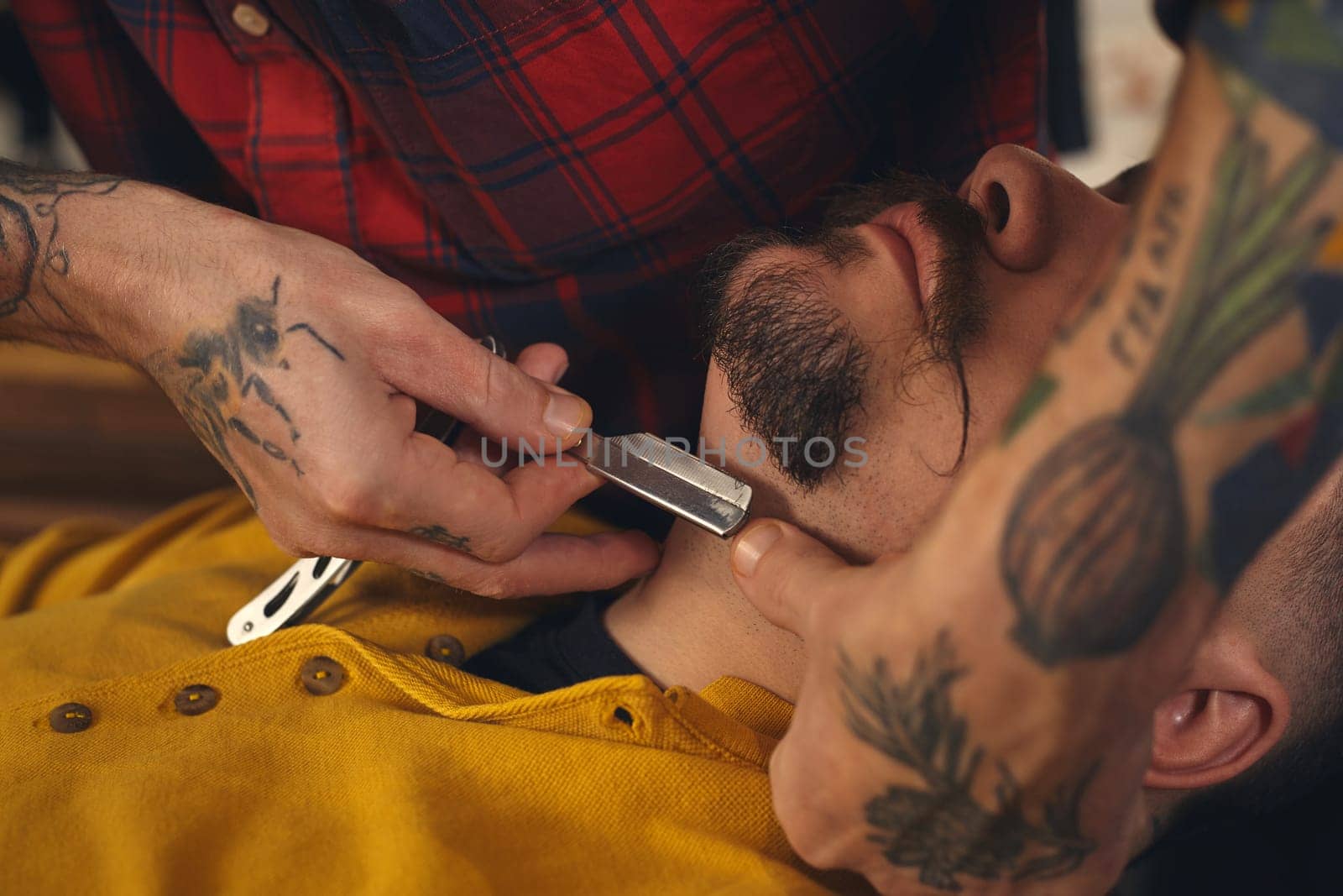 Client during beard shaving in barber shop by nazarovsergey