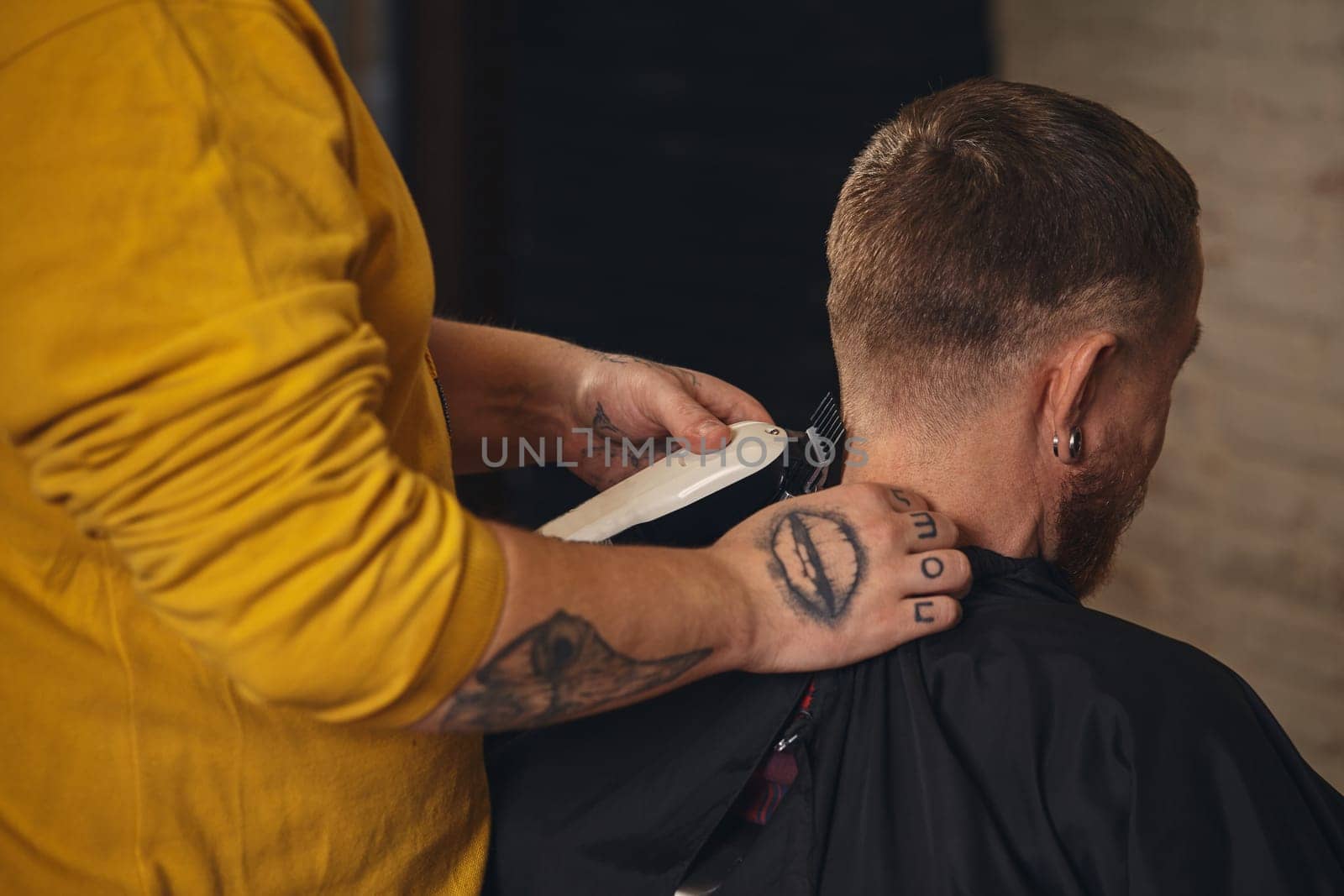 Barber making haircut of attractive bearded man in barbershop by nazarovsergey
