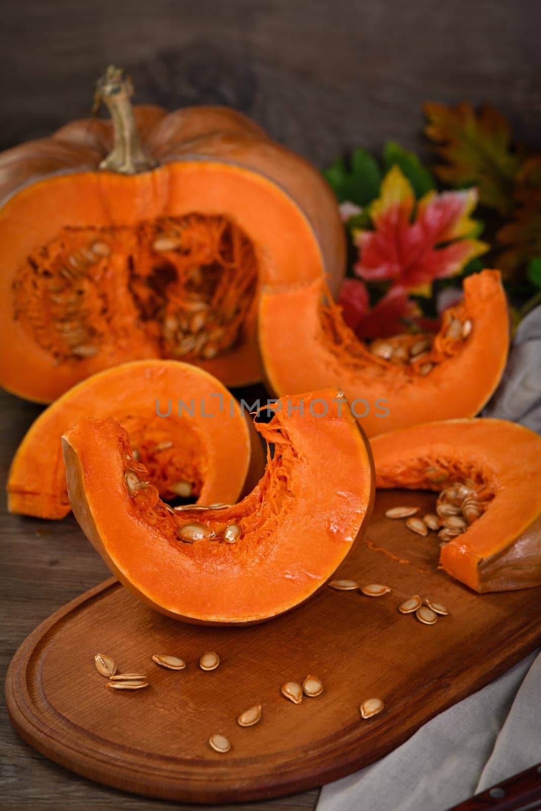 Whole fresh orange big pumpkin and slice of pumpkin on wooden board, closeup. Organic vegetable product, ingredients for cooking, healthy food vegan