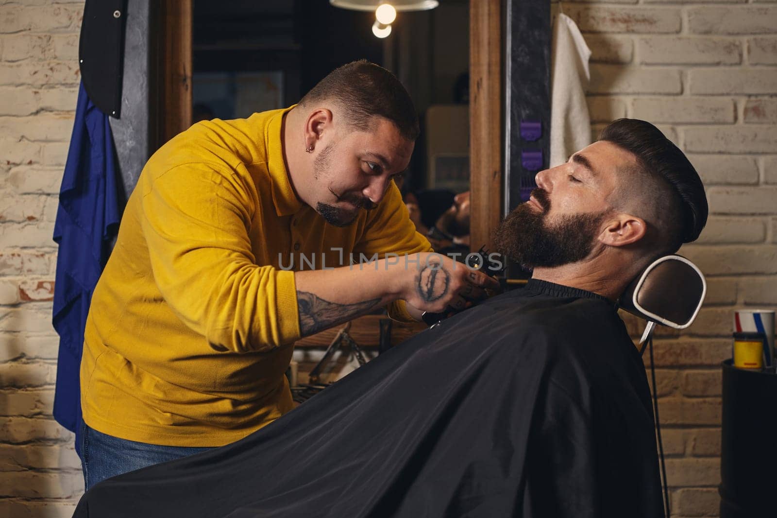 Client with big black beard during beard shaving in barber shop by nazarovsergey