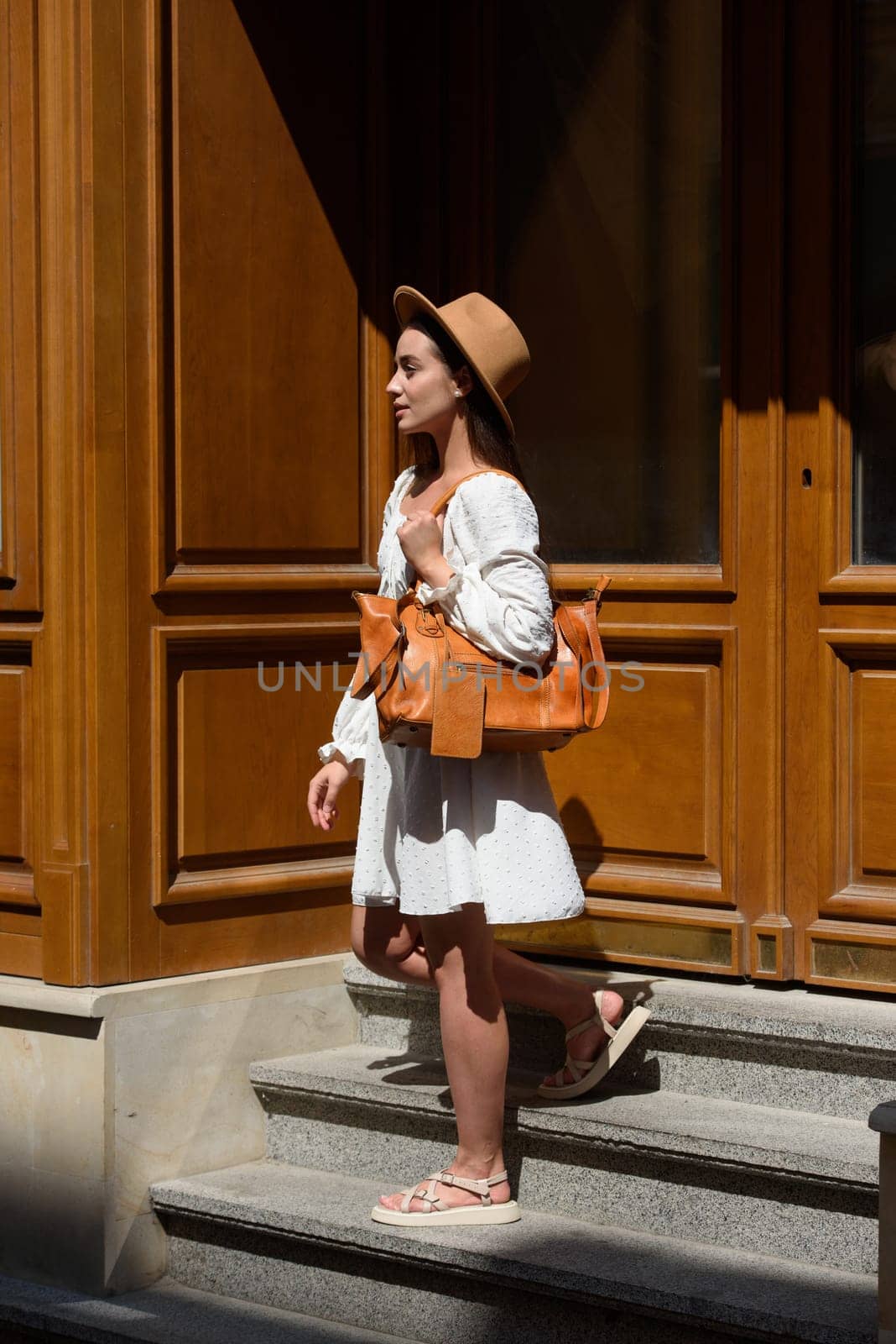 brunette with long hair wearing white romantic summer dress and beige hat posing with luxury leather bag by Ashtray25