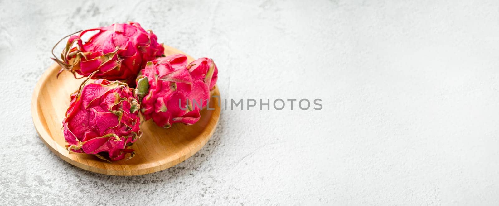 Ripe red dragon fruit on stone table by Sonat