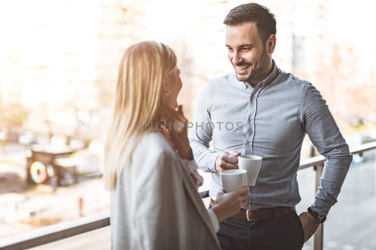 Business and a bit of fresh air on their coffee break on the balcony in front of office.