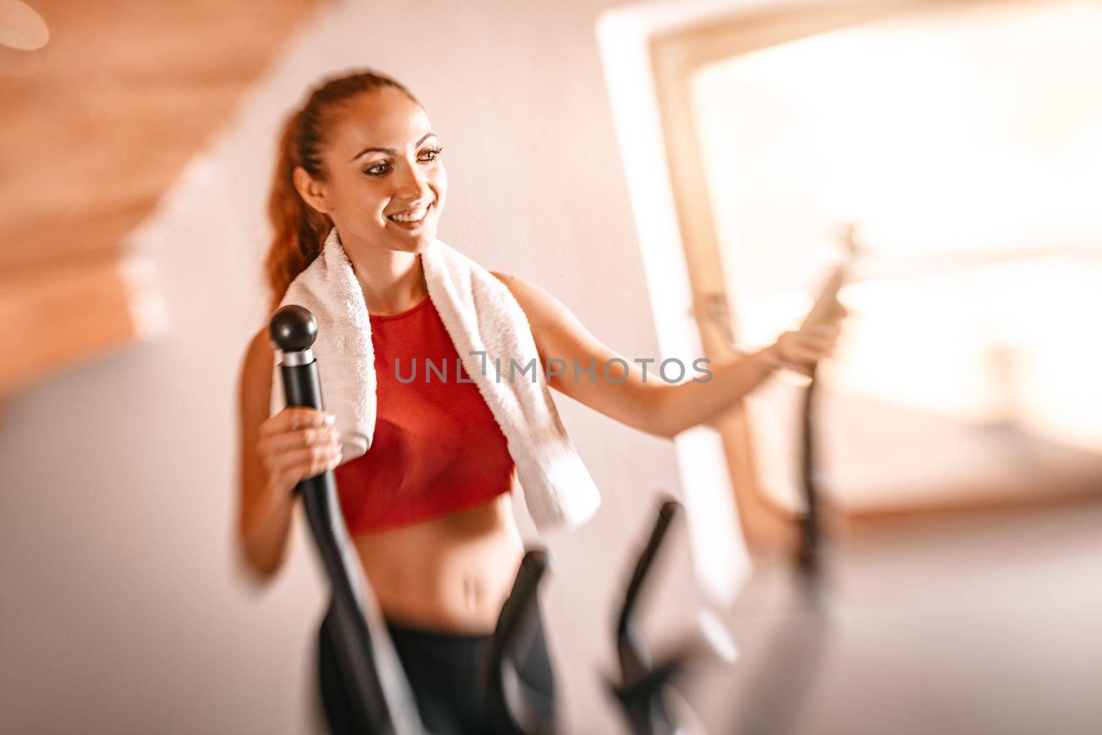 Beautiful young woman exercising on stepper at  home.