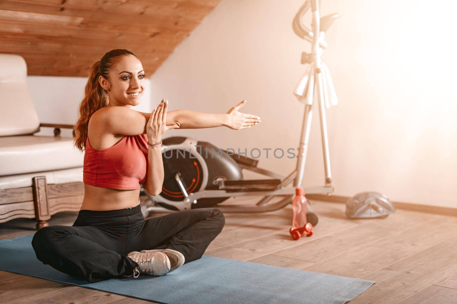 Beautiful young woman doing stretching exercises at home.