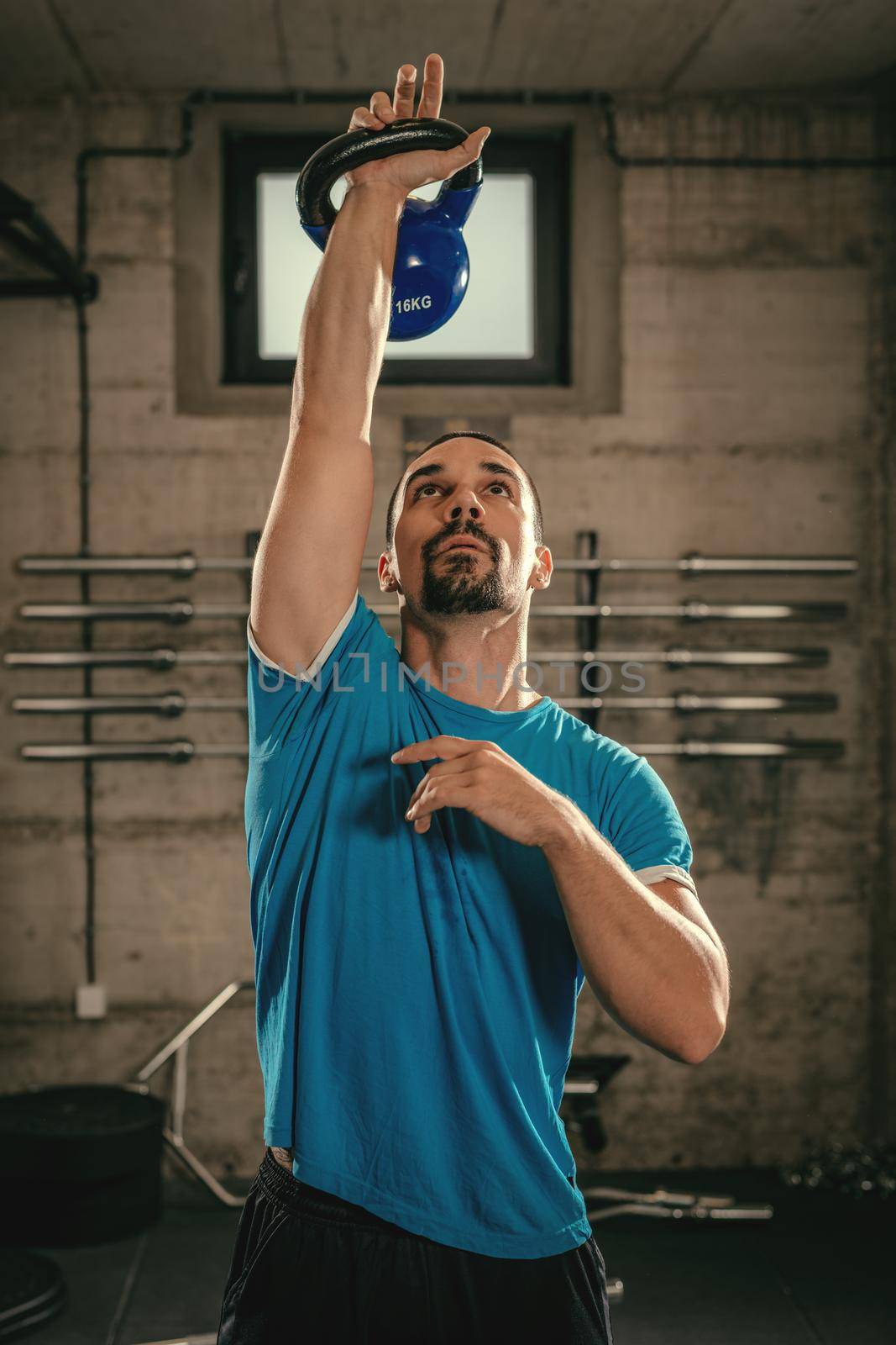 Young muscular man ready to exercise with kettlebell at the gym.