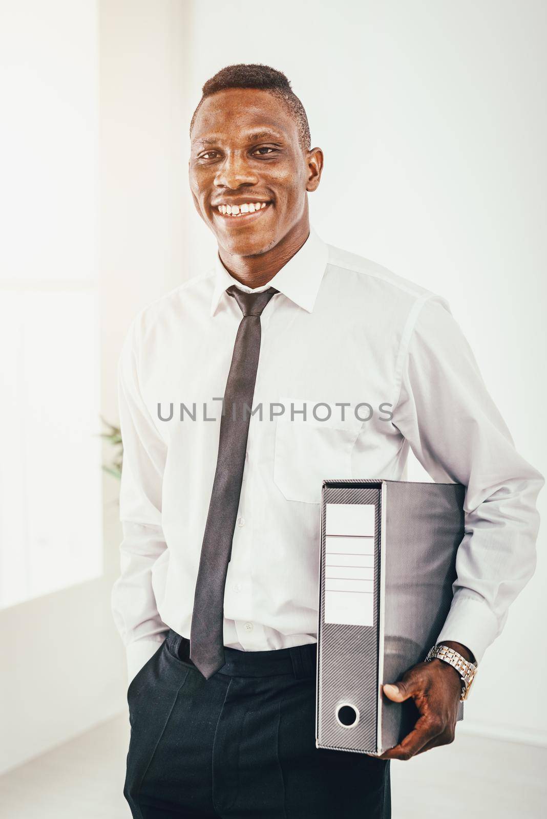 Successful African businessman is holding a folder in modern office and planning what to do next.