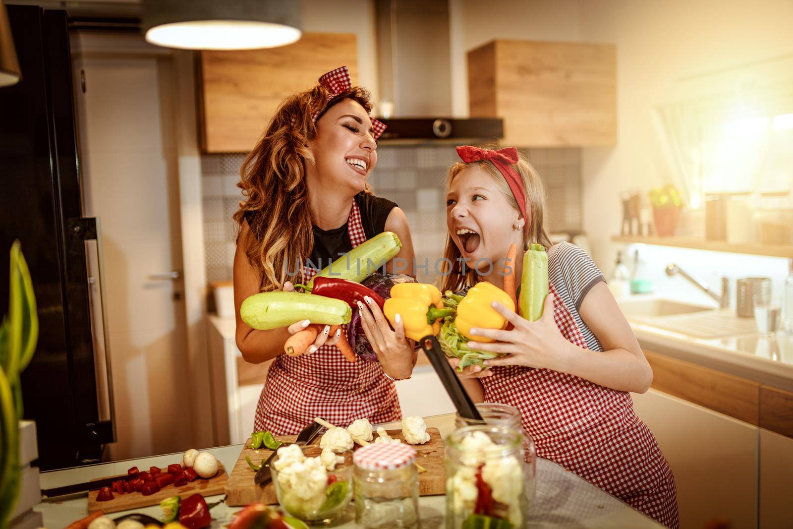Happy mother and her daughter enjoy preparing for marinating vegetables and making healthy meal together at their home kitchen.  