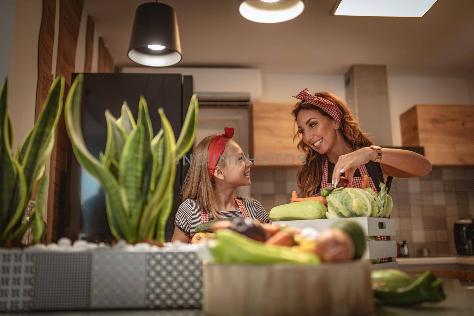 Happy mother and her daughter enjoy making and having healthy meal together at their home kitchen.