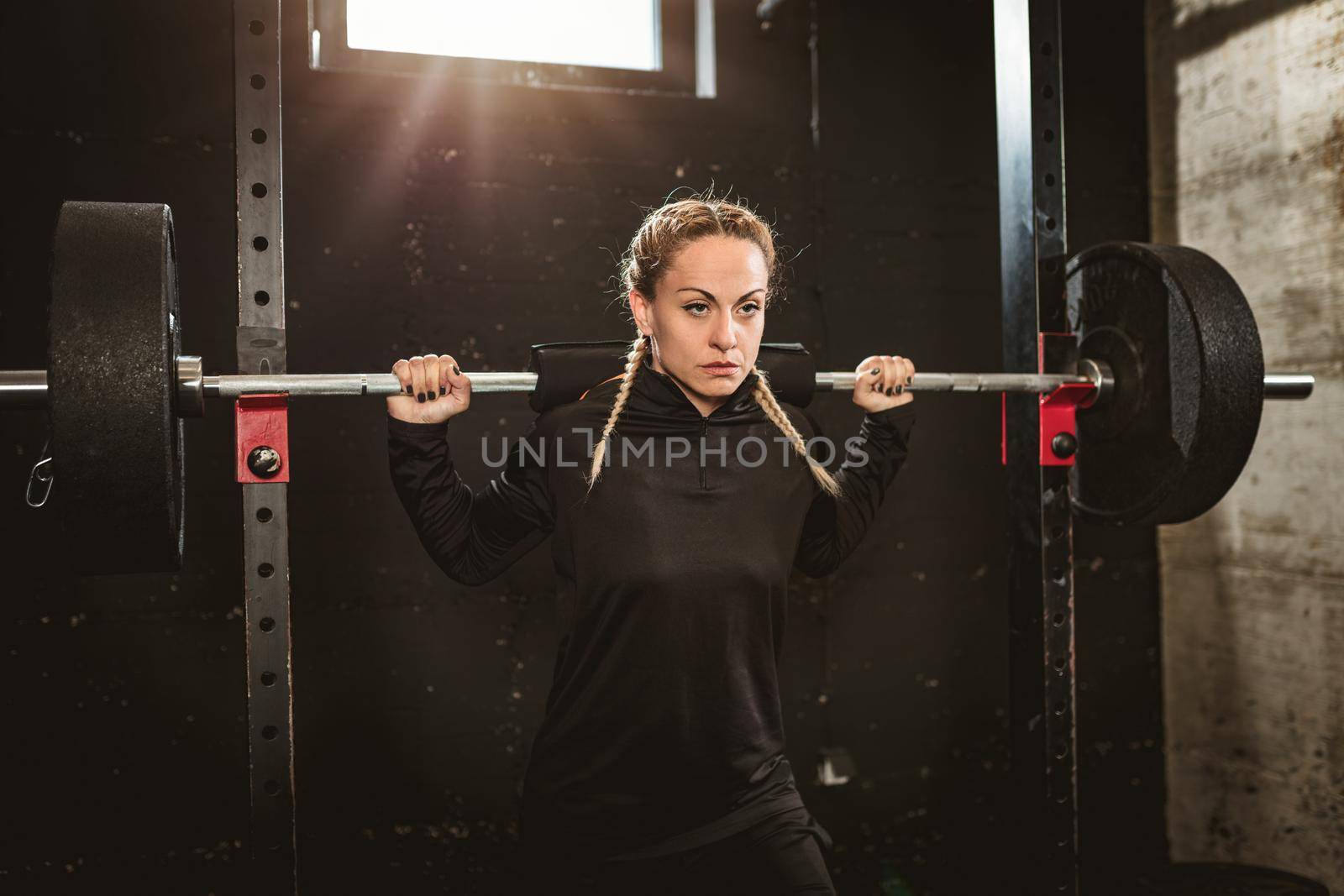 Young muscular  beautiful woman doing exercise with barbell at the gym. 