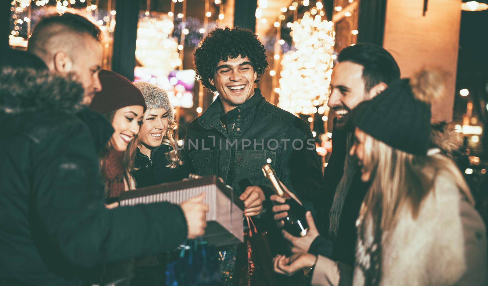 Cheerful young friends having fun at Christmas outdoor party in the city street at night.