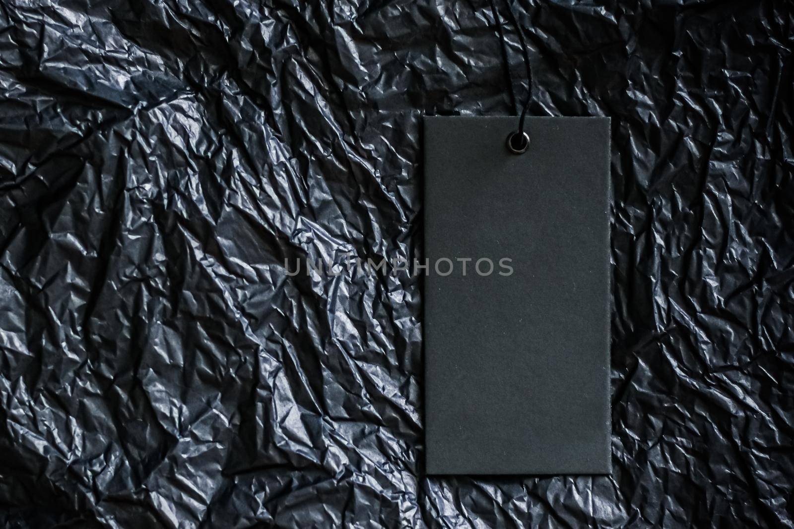 Empty clothing tag on black bakground with copyspace, sustainable fashion and brand label concept.