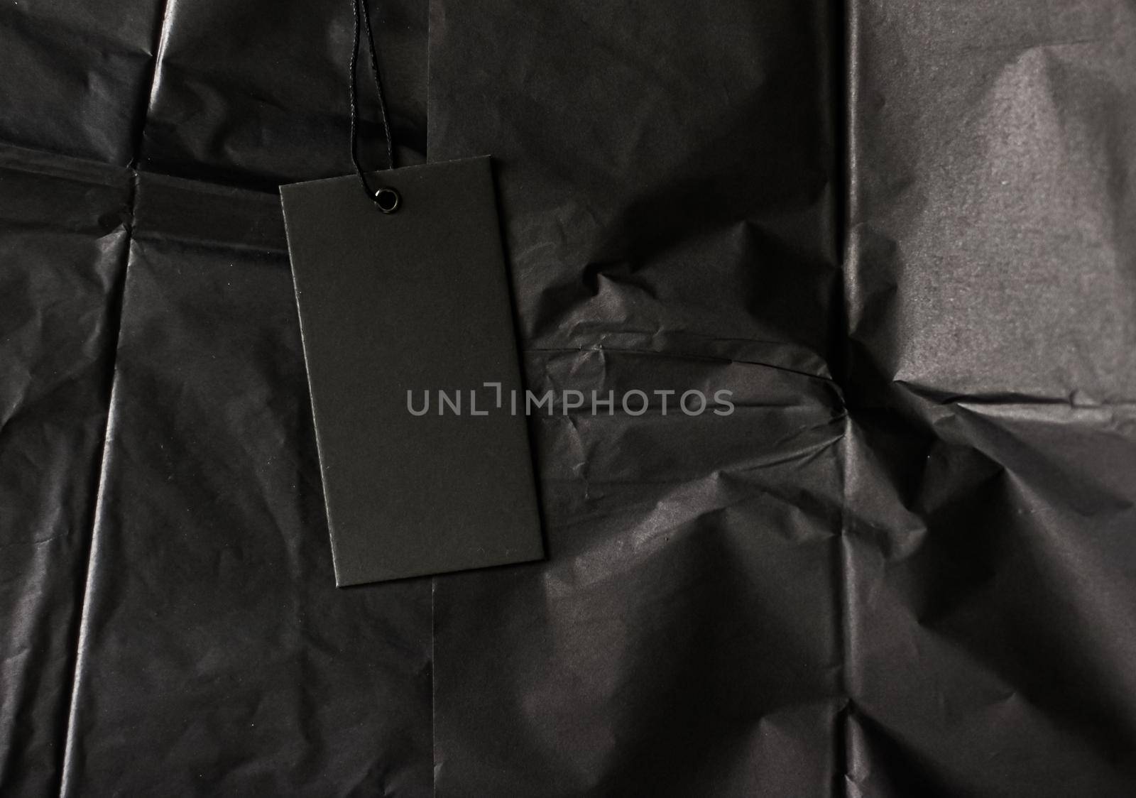 Black tag on tissue paper as luxury shopping flatlay, sustainable fashion and brand label concept.