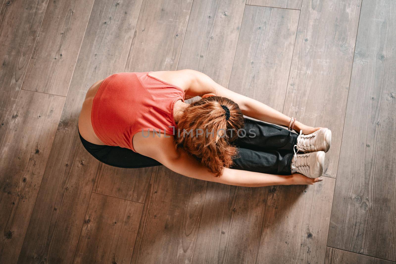 Above view of a woman doing stretching exercises on floor.