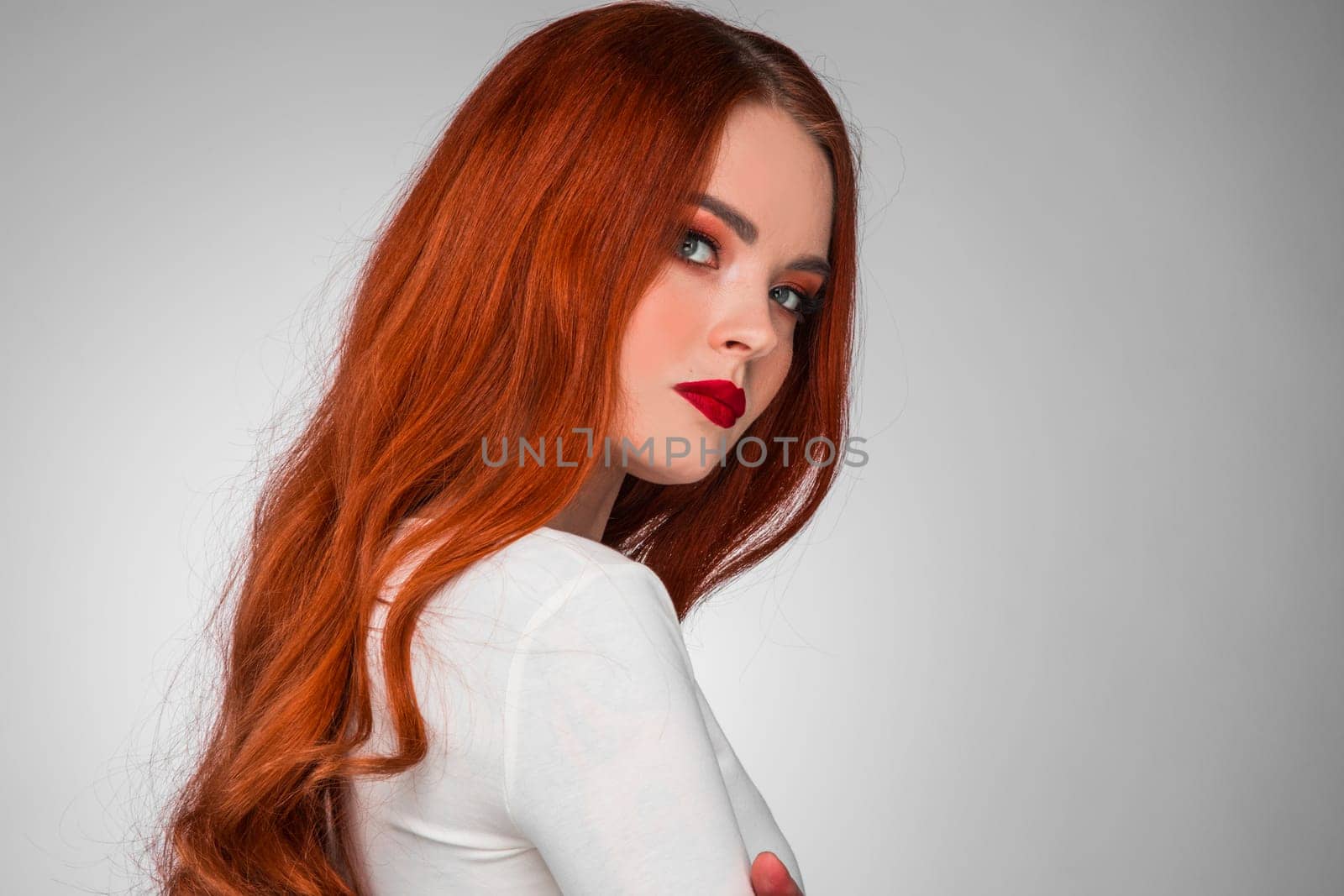 Gorgeous redhead girl with wavy hair beauty studio portrait