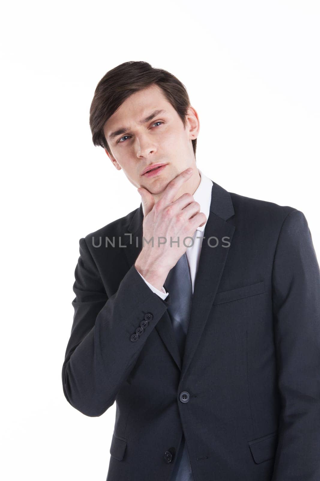 Portrait young business man holding hand in his chin while looking pensively at the camera isolated on white background