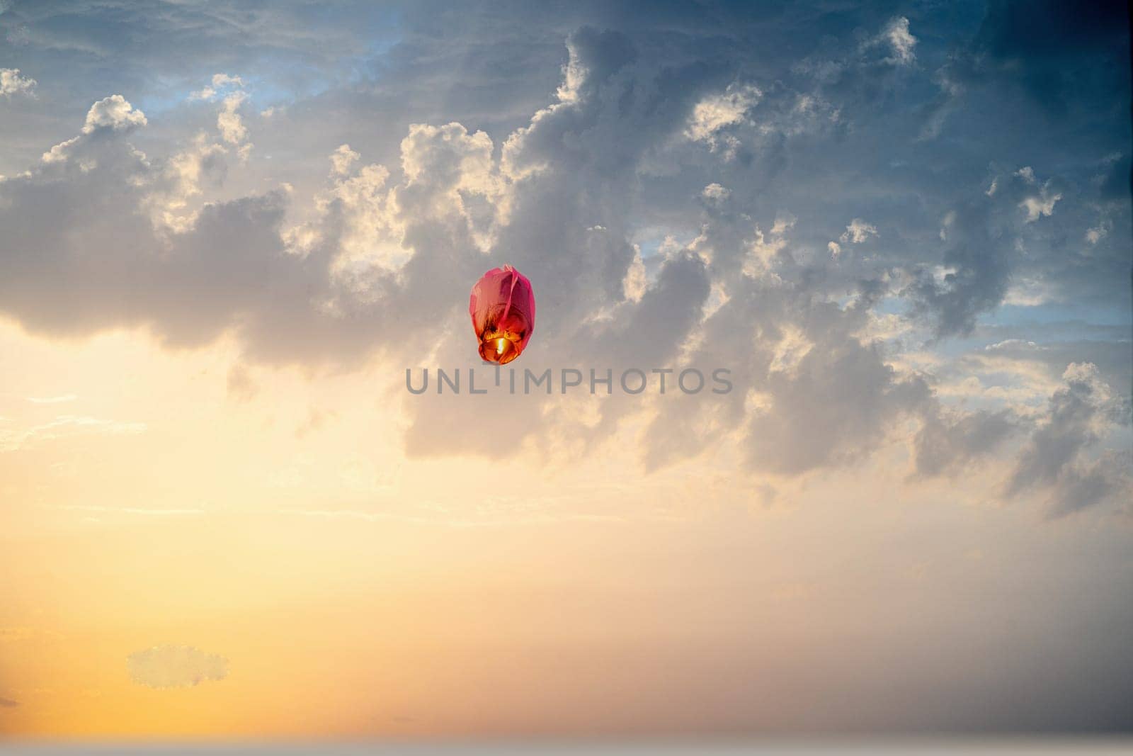 orange sky lantern floating in the middle of grey sky on the festival of independence day makar sankranti uttarayan India