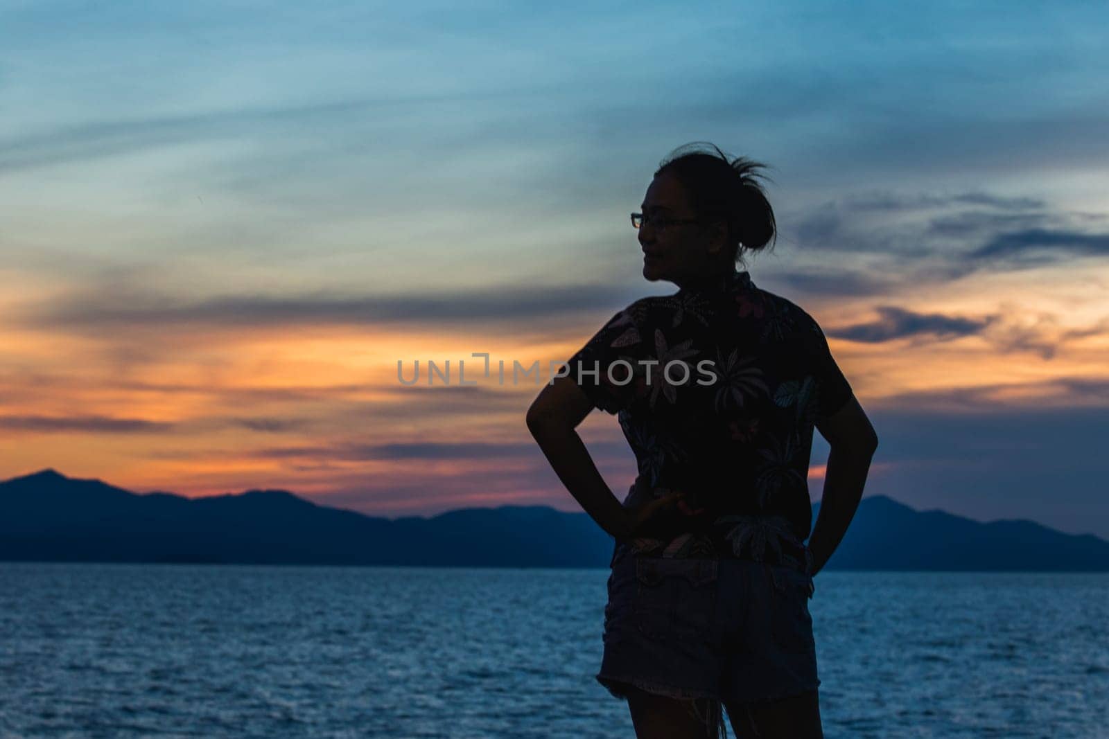 Silhouette of a woman standing and watching the sunset