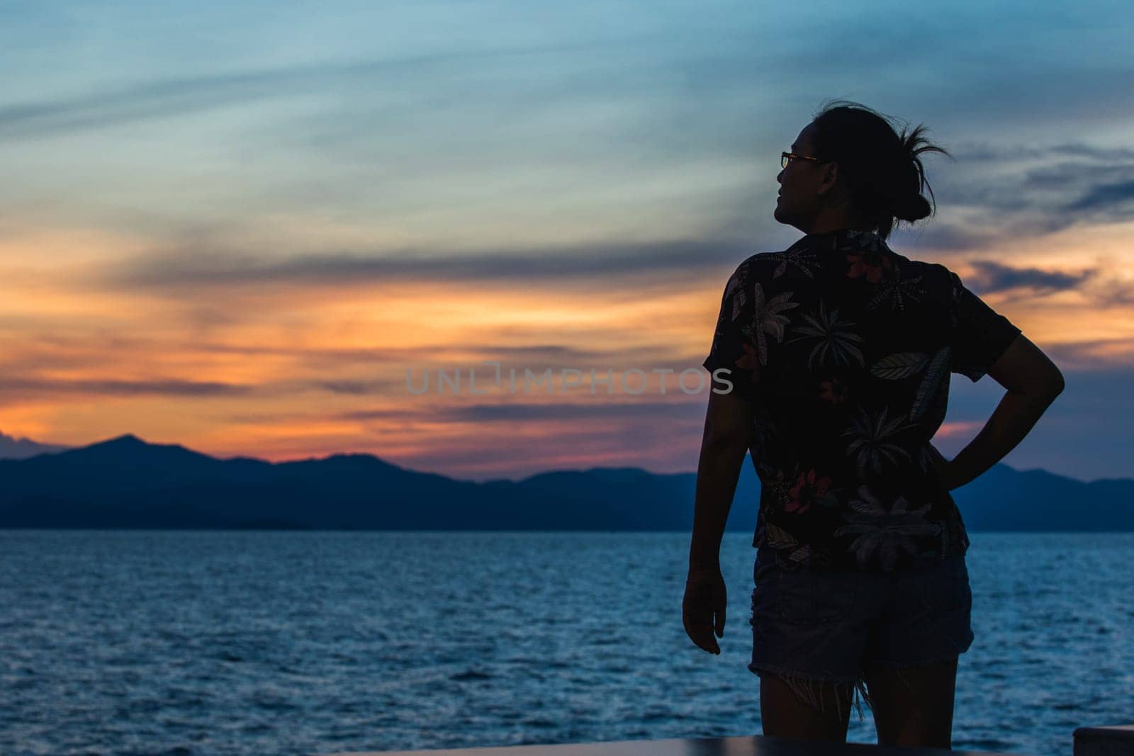 Silhouette of a woman standing and watching the sunset