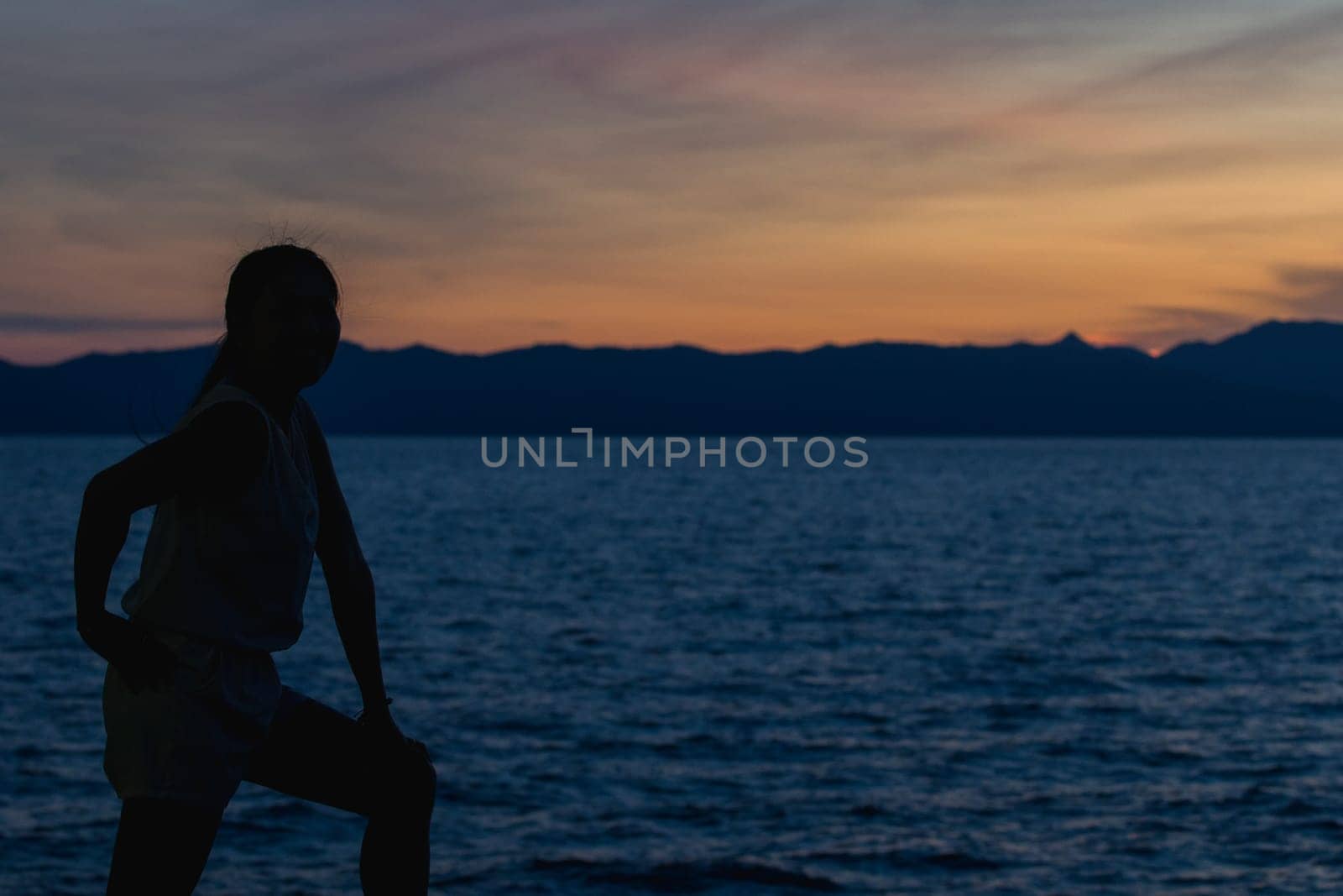 Silhouette of a woman standing and watching the sunset