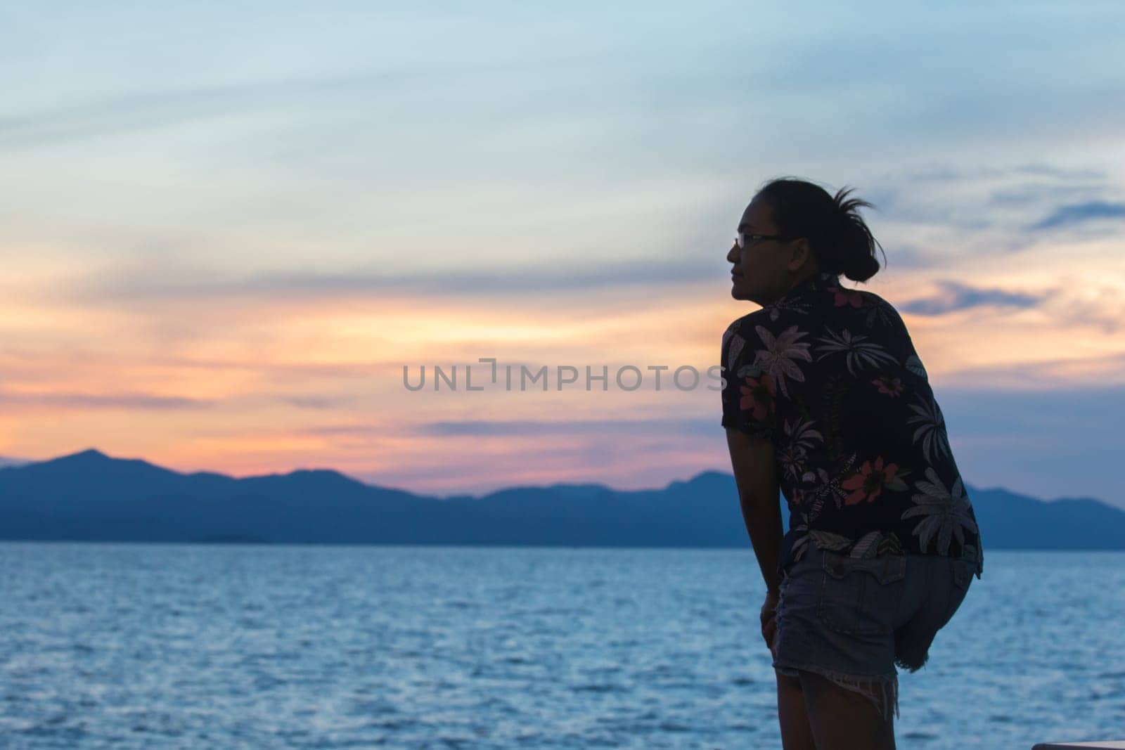 Silhouette of a woman standing and watching the sunset