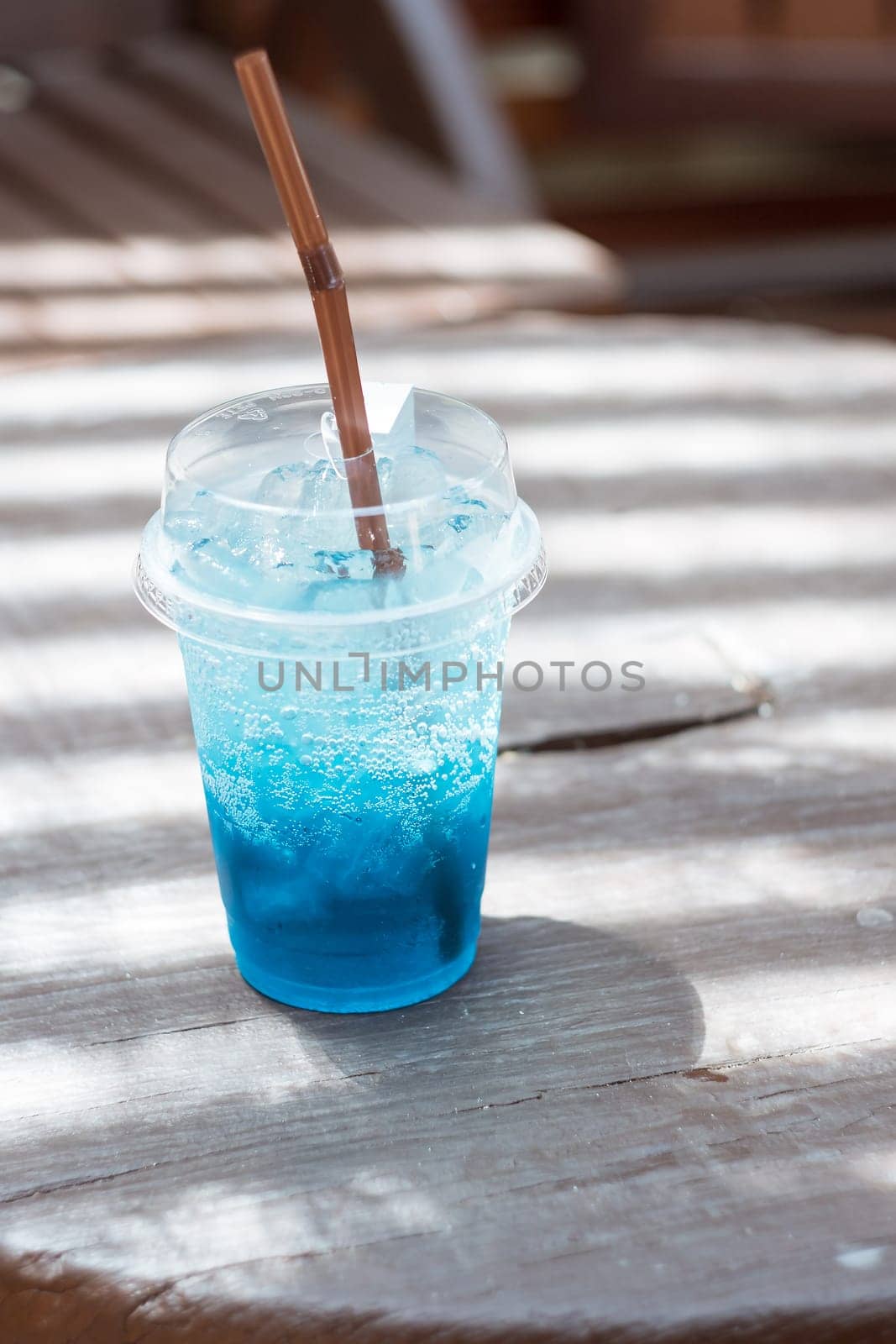 Blue soda in a plastic glass placed on a wooden table