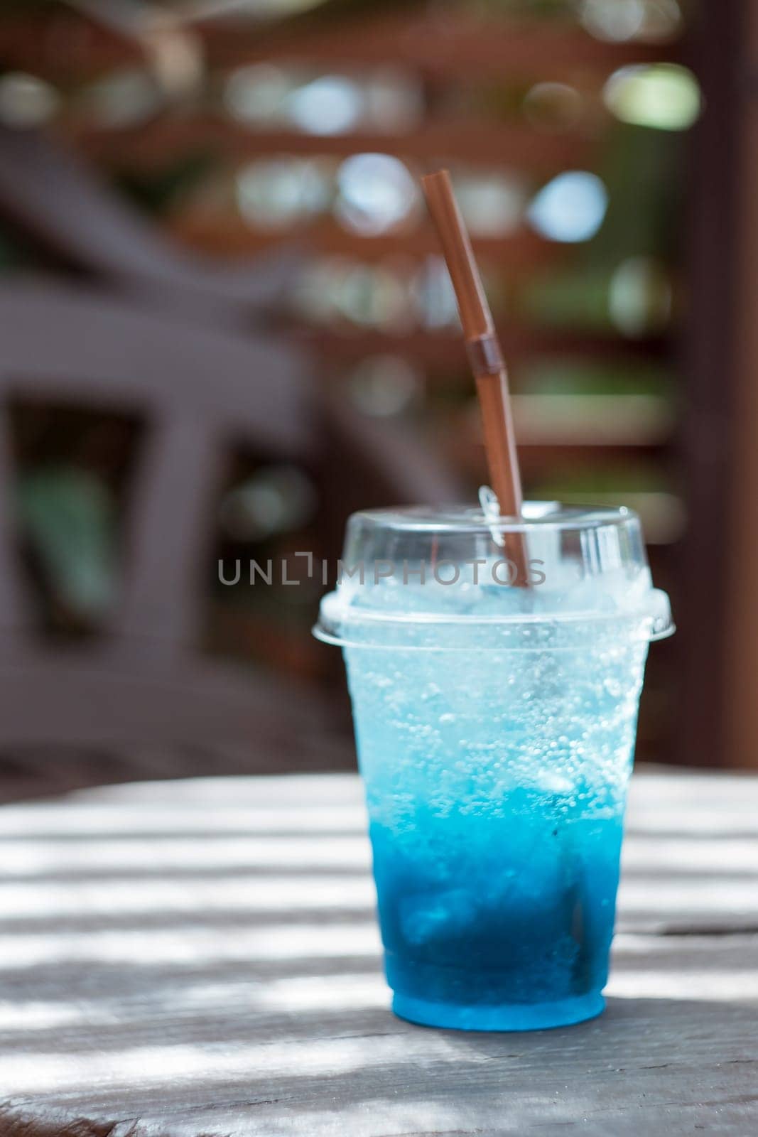 Blue soda in a plastic glass placed on a wooden table