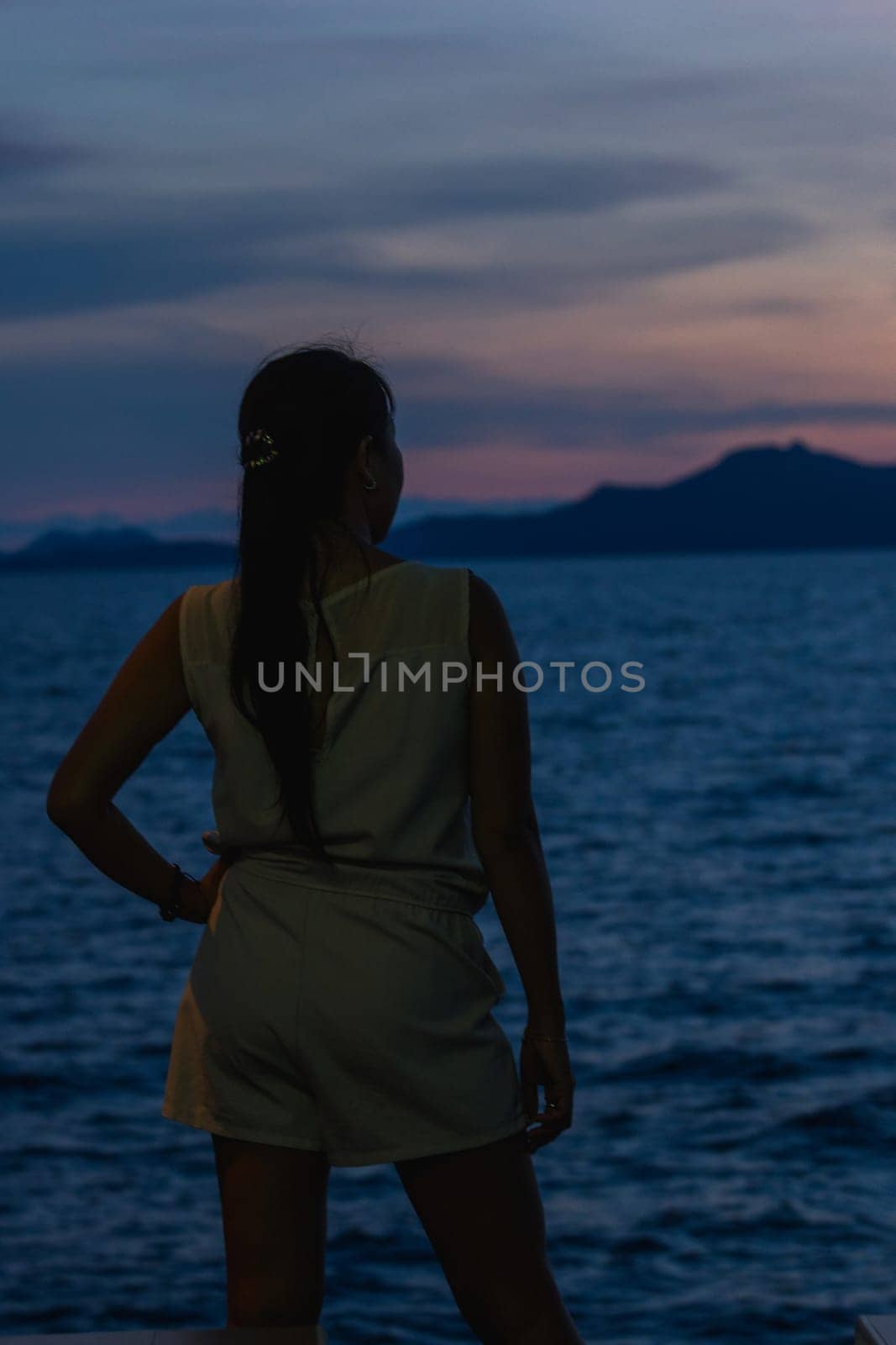 Silhouette of a woman standing with the sunset in the beautiful sea