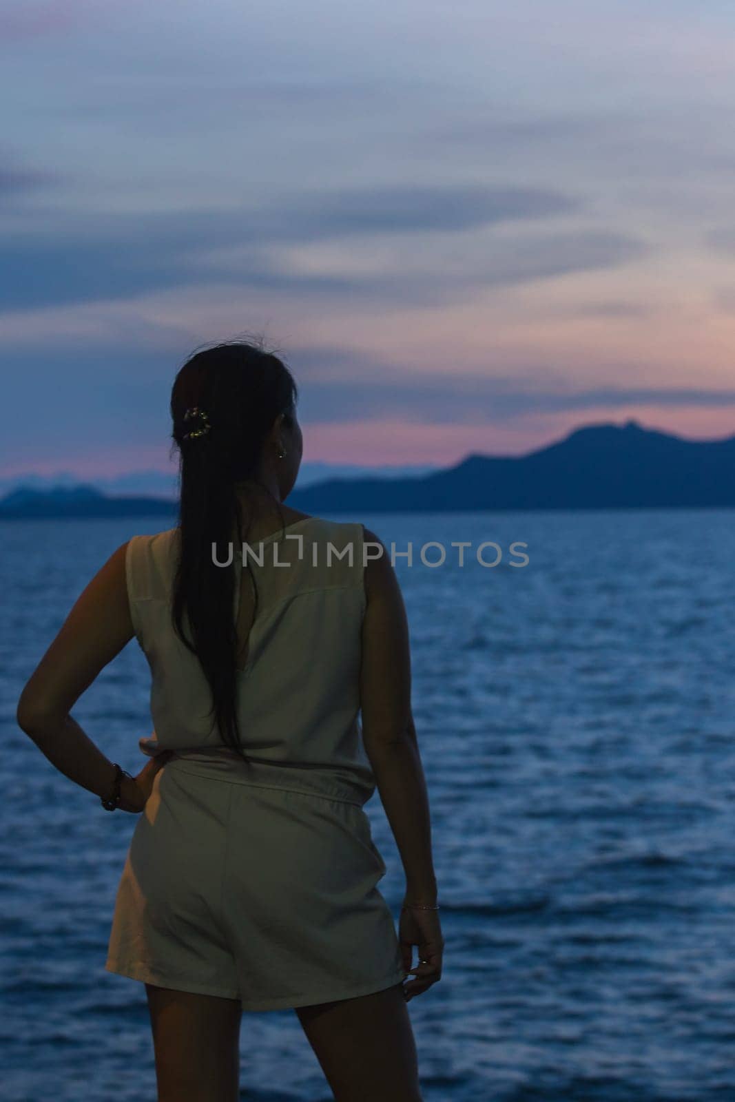 Silhouette of a woman standing with the sunset in the beautiful sea