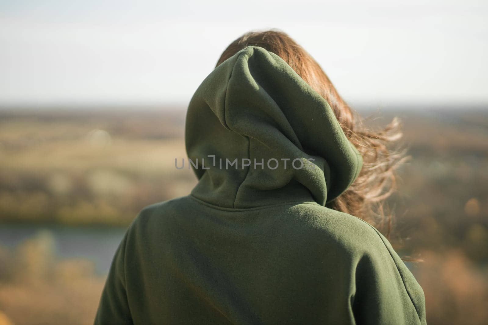Rear view of trendy young woman in dark green hoodie in autumn. Cute model walks in park in golden autumn through colorful trees and fallen leaves. Autumn fall walk colorful nature by Satura86