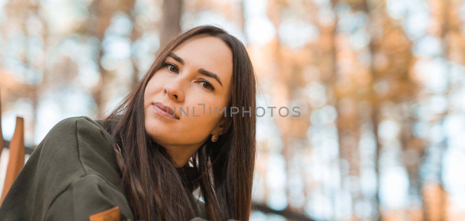 Banner Attractive stylish woman walking in park dressed in warm hoodie copy space. Pretty girl smiles. Autumn urban street fashion style. Fall season by Satura86