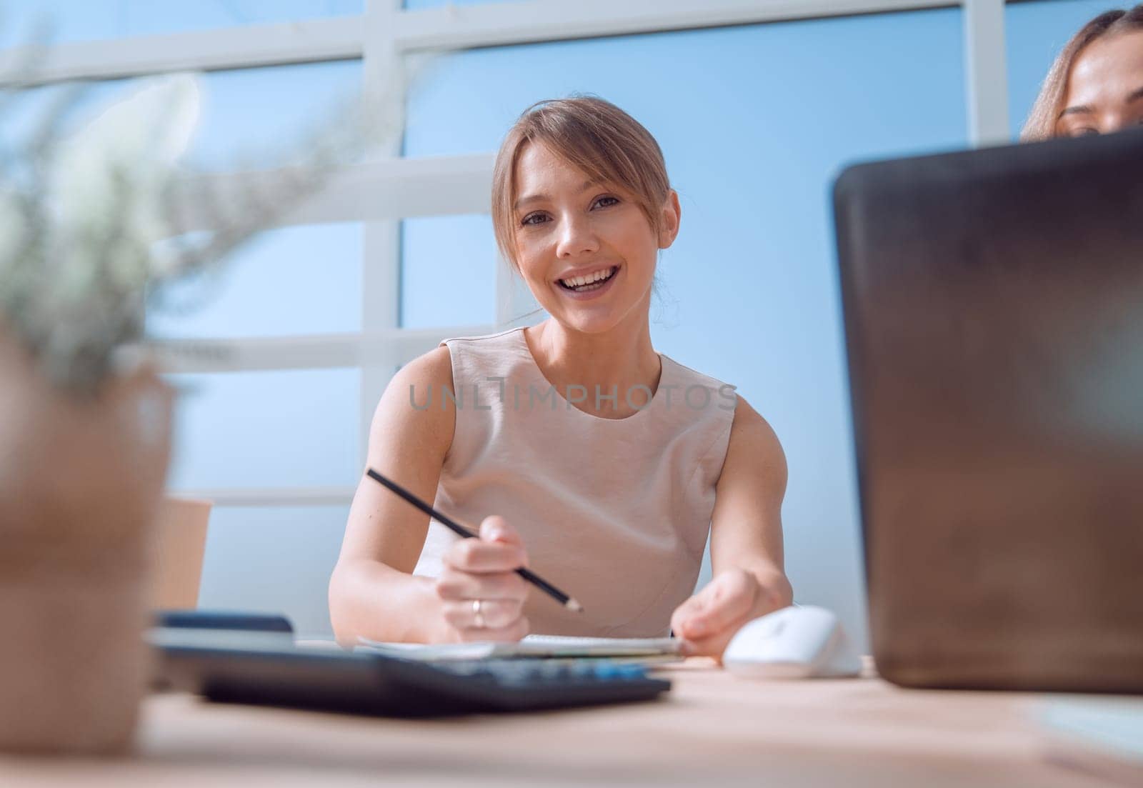 young business woman sitting at office Desk by asdf