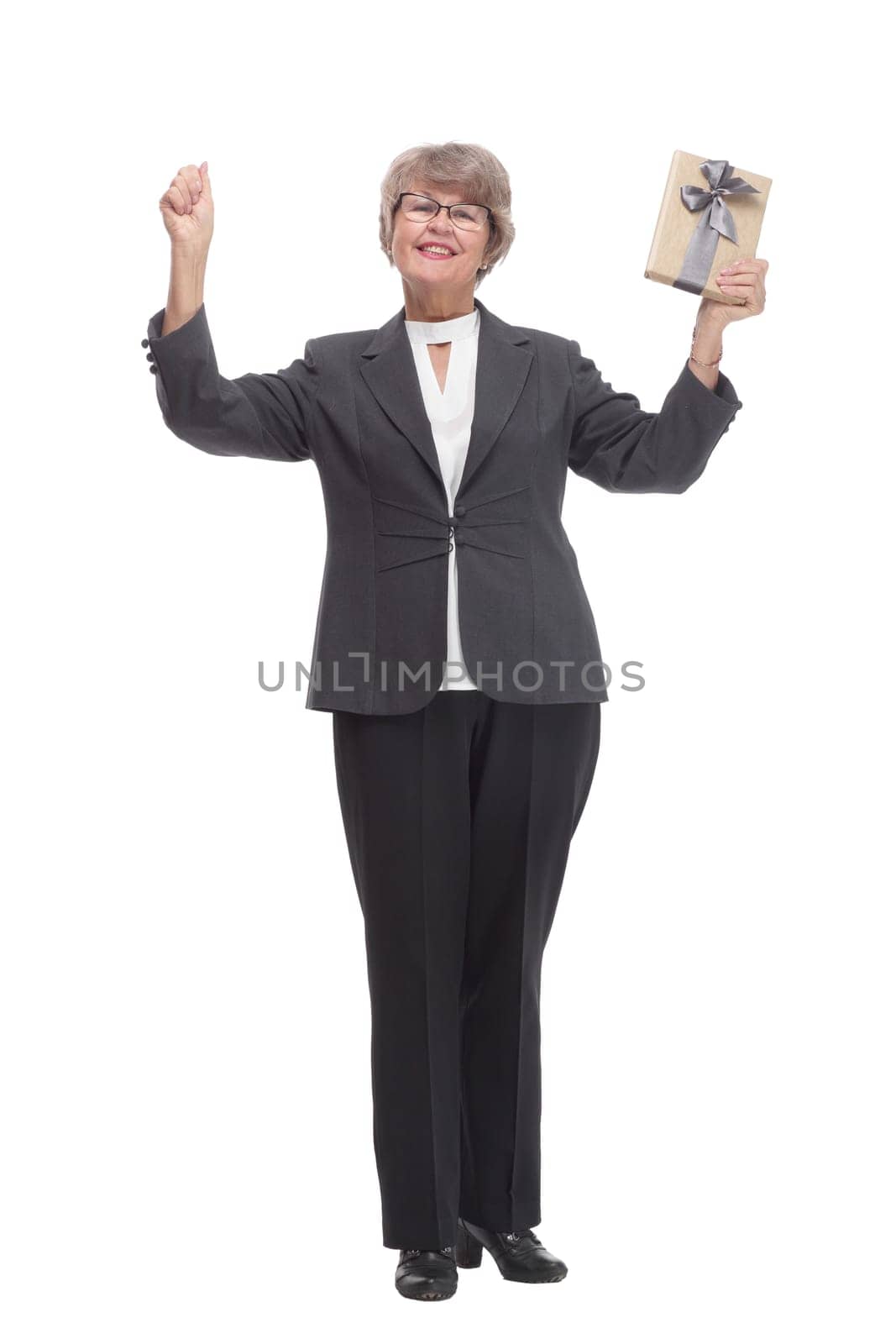 Full body senior woman happy and smiling, holding a gift and pointed on it looking at camera