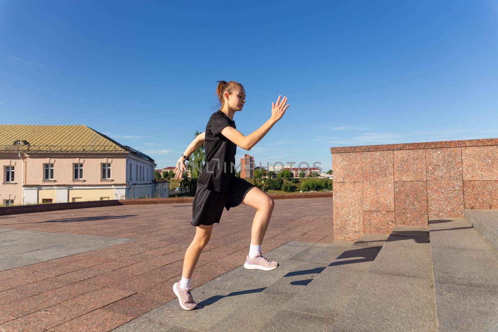 A young woman in black clothes running on stairs at city street early morning.