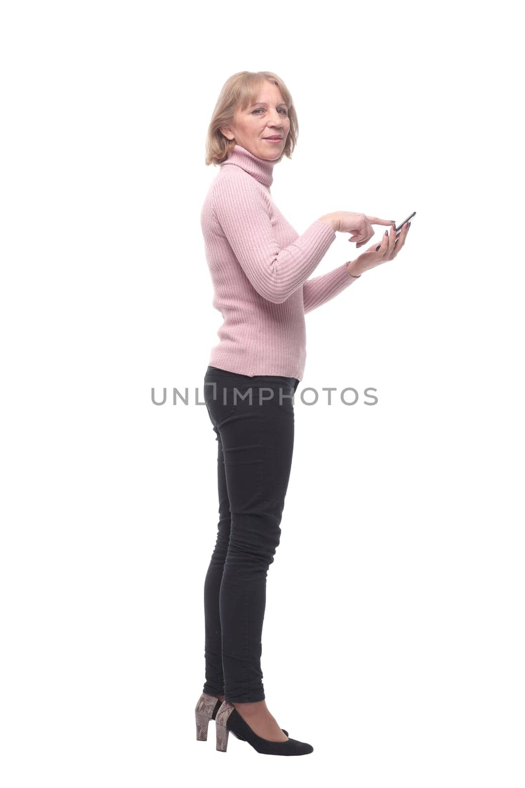 Side view of pretty lady looking at her cell phone screen and standing against white background