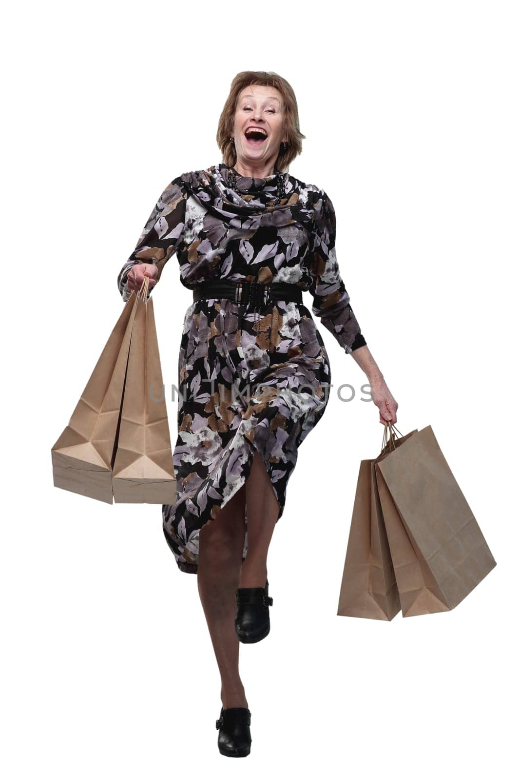 Caucasian senior woman walking with shopping bags smiling at viewer. Concept of successful shopping