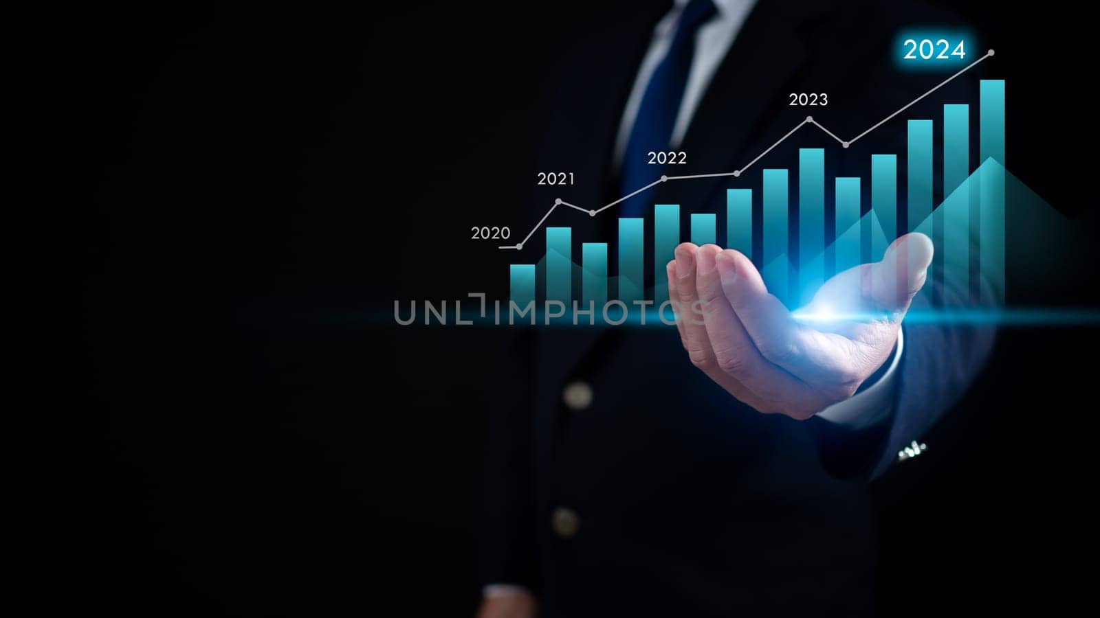 Stock trading. Finance. Investing. Growing business. Businessman in a suit is holding a virtual graph It represents growth of stocks and business in 2024.