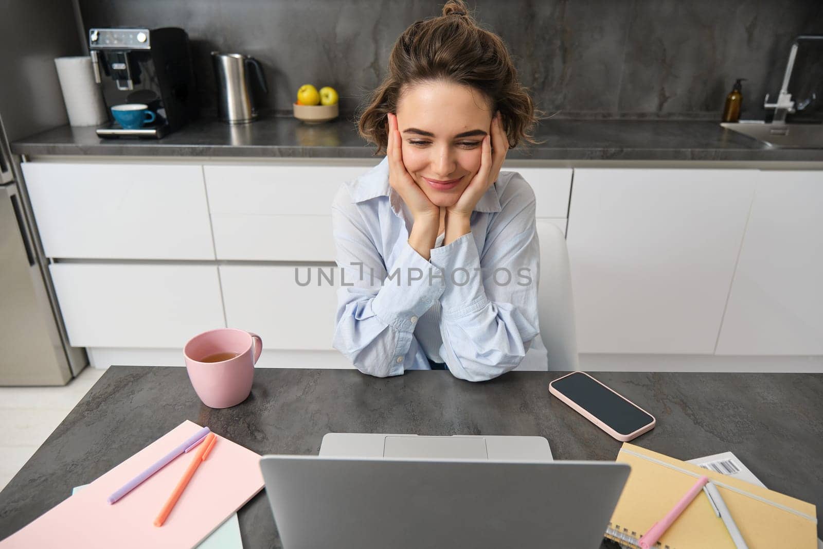 Top view of businesswoman working from home. Girl studies remotely on laptop, sits in kitchen and looks at screen, watches webinar, online course.