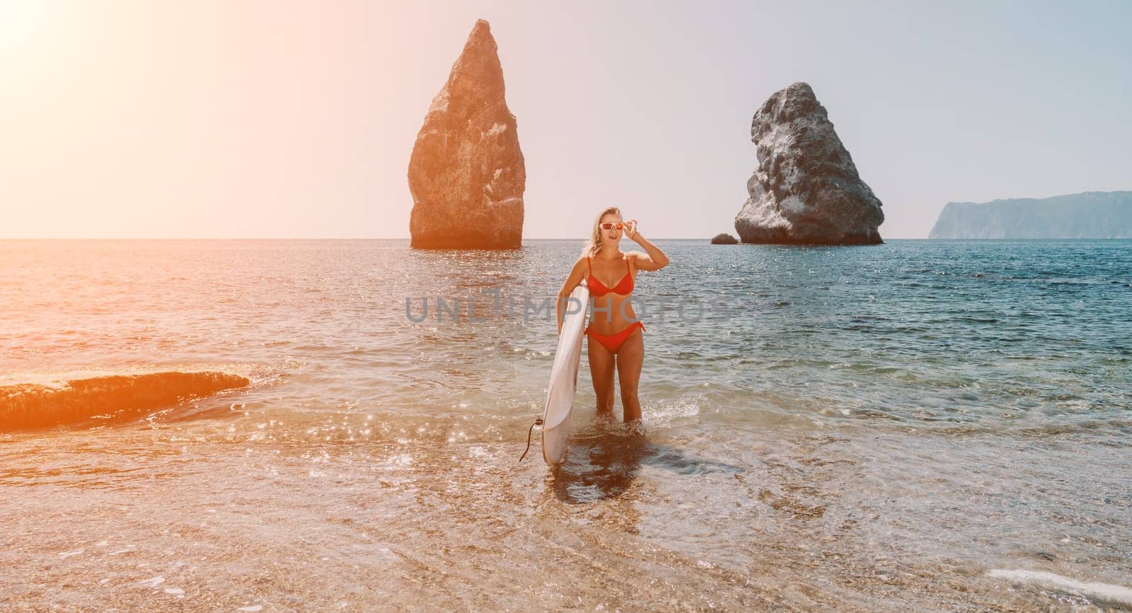 Woman sea sup. Close up portrait of happy young caucasian woman with blond hair looking at camera and smiling. Cute woman portrait in red bikini posing on sup board in the sea by panophotograph